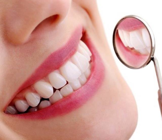 Close up of woman’s teeth in dental mirror